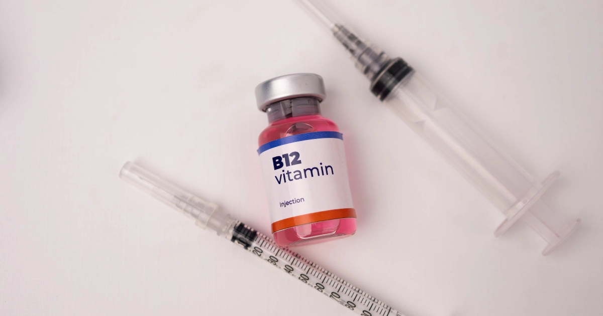 Pink Vitamin B12 injection solution and two syringes on a white surface, representing Vitamin B12 Injections in Charleston, SC.